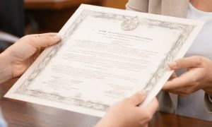 Pessoa recebendo uma certidão em mãos no balcão de um cartório, com expressão de satisfação e atenção