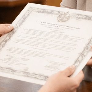 Pessoa recebendo uma certidão em mãos no balcão de um cartório, com expressão de satisfação e atenção