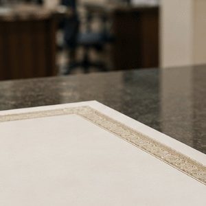 Certidão sobre a mesa ao lado de uma maquete de casa em um ambiente de cartório, representando processos ligados a imóveis e documentação oficial.