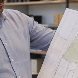 Especialista analisando a planta de um terreno para realizar o desmembramento, em um ambiente profissional e bem iluminado